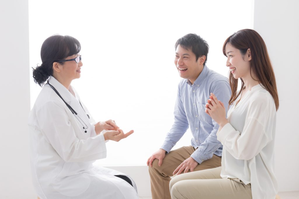 女性医師と笑顔で話す夫婦